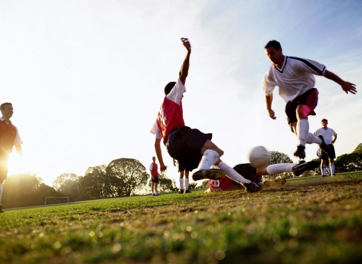 A group of people playing soccer on the grass.